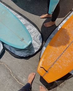 two people standing next to surfboards on the ground