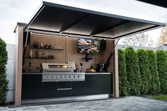 an outdoor kitchen is built into the side of a house with lots of greenery