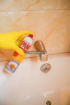 a person in yellow rubber gloves is cleaning a sink with pam deterant on it