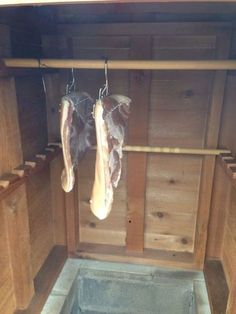 two meats hanging from hooks in a wooden stall