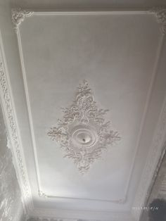 the ceiling in this room is painted white and has intricate designs on it's walls