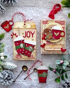 two christmas cards with ornaments and decorations on the table next to pineconi cones