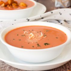 two white bowls filled with soup on top of a table