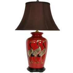 a red vase with two birds on it and a brown lamp next to the base