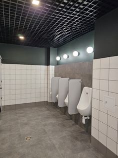 a row of urinals in a bathroom with tiled walls and flooring on the ceiling