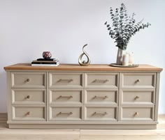 a white dresser with drawers and vases on top