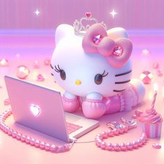 a hello kitty doll sitting on top of a laptop computer next to a cupcake