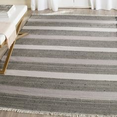 a large rug in the middle of a living room with white drapes on the windowsill