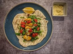 a blue plate topped with a tortilla covered in veggies