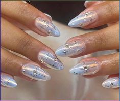 a woman's hands with white and silver nail polishes on their nails, holding a dandelion design