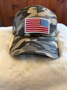 American Flag patch on a camo hat with adjustable closure Military Camouflage Baseball Cap, Military Cap For Memorial Day, Military Style Khaki Trucker Hat, Military Style Trucker Hat, Military Hat With Adjustable Logo Patch, Military Style Khaki Trucker Hat Snapback, Adjustable Hat For Veterans Day Outdoor Events, Military Style Khaki Snapback Trucker Hat, Snapback Baseball Cap For Memorial Day Outdoor