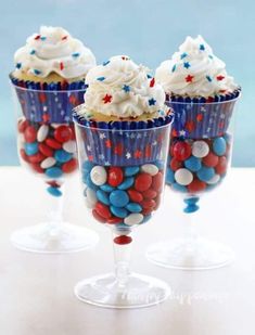 three cupcakes with red, white and blue frosting on them in wine glasses