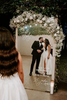 a bride and groom kissing in front of a wedding photo