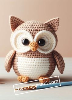 a crocheted owl sitting on top of a table next to a blue pencil