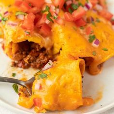 a white plate topped with an enchilada covered in cheese and toppings