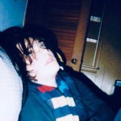 a young man laying on top of a bed next to a door and pillows in front of him