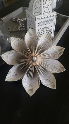 a paper flower sitting on top of a table next to a candle holder and lantern