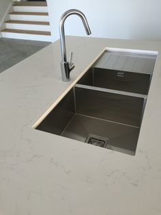 a kitchen sink sitting under a faucet on top of a white countertop