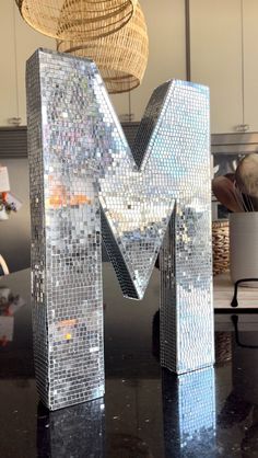 the letter m is made out of small mosaic tiles and sits on top of a table