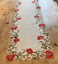 an embroidered table runner with red flowers on it