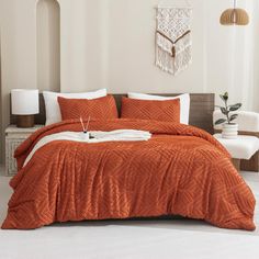 a bed with an orange comforter and pillows