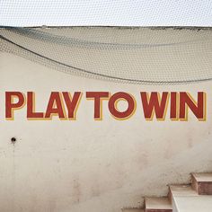 there is a sign that says play to win on the side of a building with stairs