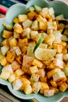 a blue bowl filled with potatoes and cucumbers