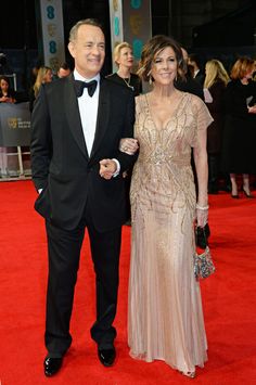 a man and woman in formal wear on the red carpet at an awards event together