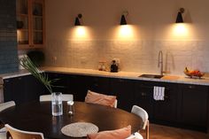 a kitchen with a table, sink and lights on the wall above it's counter