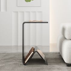 a small table with a book on it next to a white chair and a painting