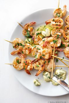 shrimp skewers are served on a white plate