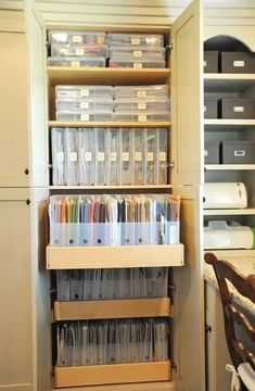 an organized pantry with clear plastic containers and file folders on the bottom shelf, next to a wooden chair