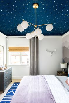 a bedroom with blue and white stars painted on the ceiling, bed in foreground