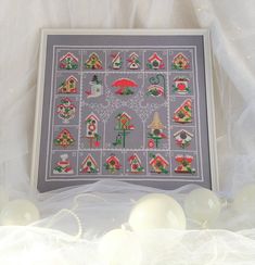 a cross stitch pattern with christmas trees and houses on it, surrounded by white balls