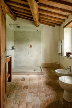 a bathroom with two sinks and a walk in shower next to a toilet under a wooden beam