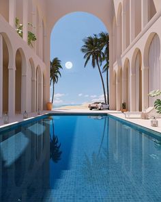 an indoor swimming pool with palm trees and the ocean in the background