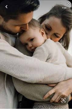 a man and woman holding a baby in their arms