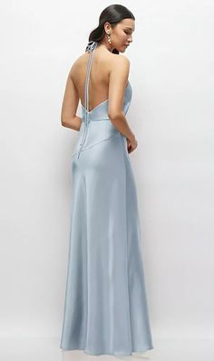 a woman in a long blue dress looking down at the back of her dress,