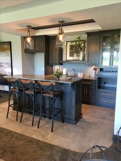 a kitchen with bar stools and an island in the middle, surrounded by dark wood cabinets