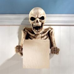 a skeleton holding a blank sign hanging from a hook on a wall in a bathroom