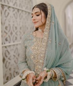 a woman in a blue and gold bridal outfit holding her hands out to the side