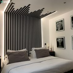 a bedroom with black and white stripes on the wall behind the bed is lit by two lamps