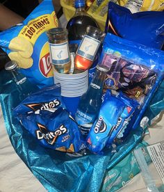 an assortment of snacks and drinks sitting on a blue table cloth with silver foil around it