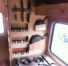 a stove top oven sitting inside of a kitchen next to two open windows with pots and pans hanging on the wall