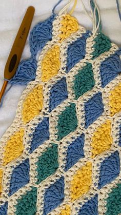 a crocheted blanket with a knitting needle next to it