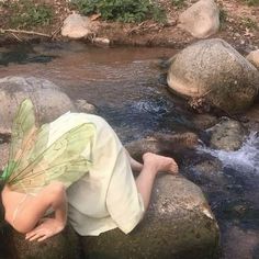 a little boy laying on some rocks in the water