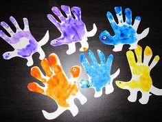 five handprints made to look like fish in different colors on a black surface