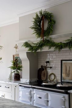 a kitchen with white cabinets and green wreaths on the wall above an old fashioned stove