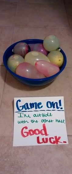 a bowl full of balloons sitting on the floor next to a sign that says come out