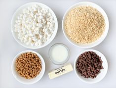 four bowls filled with different types of cereal and marshmallows next to a bottle of milk